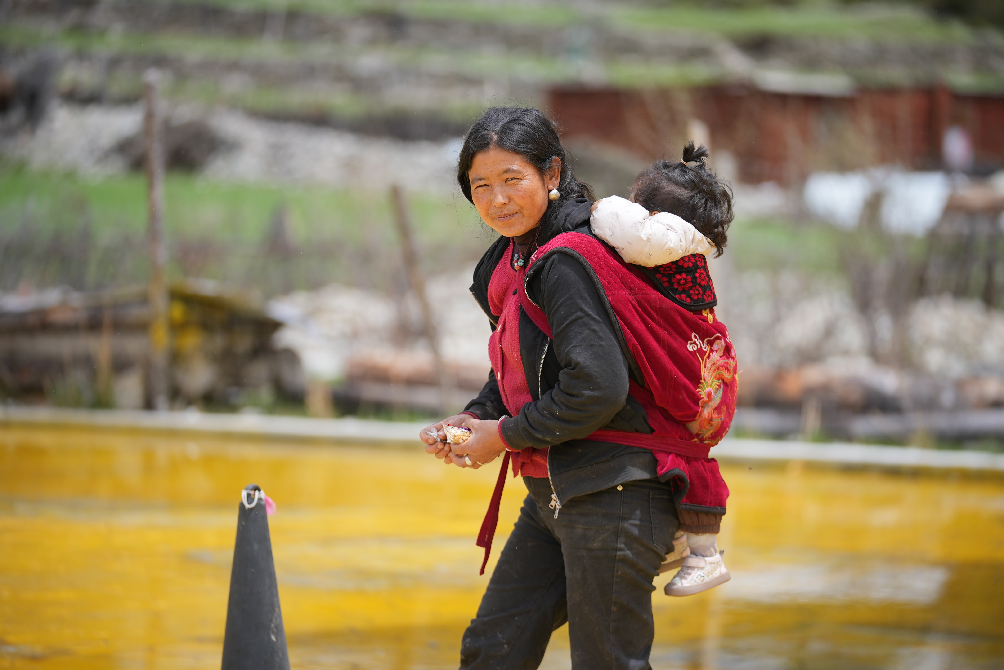 A villager carries her baby by Ranwu Lake in Baxoi County, Qamdo, Xizang Autonomous Region, China, May 17, 2026. Li Jian/CGTN