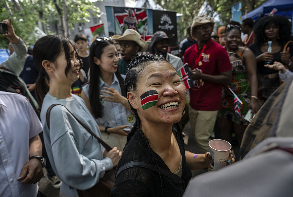 A Chinese woman has a Kenyan flag painted on her cheek as she dances with people attending the 2026 Africa Day Cultural Festival in Beijing, China, May 23, 2026. /VCG