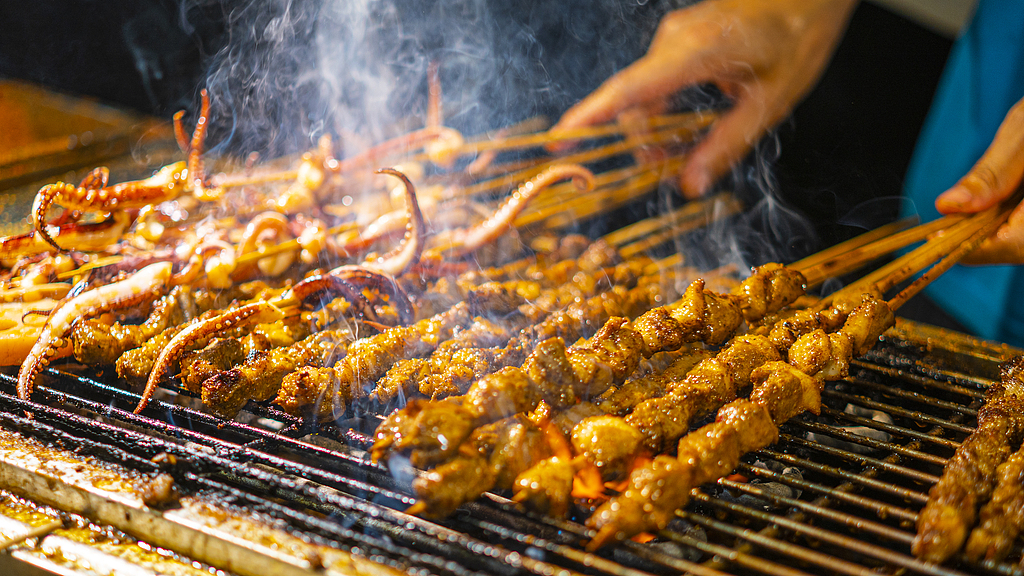 A close-up of a chef grilling skewers. /VCG 