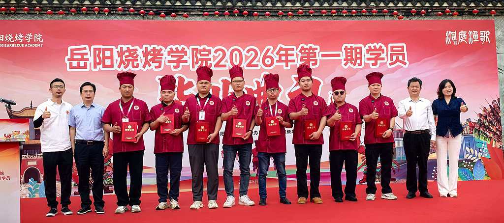 The first batch of graduates from the Yueyang Barbecue Academy pose for a photo in Hunan Province on May 20, 2026. /VCG