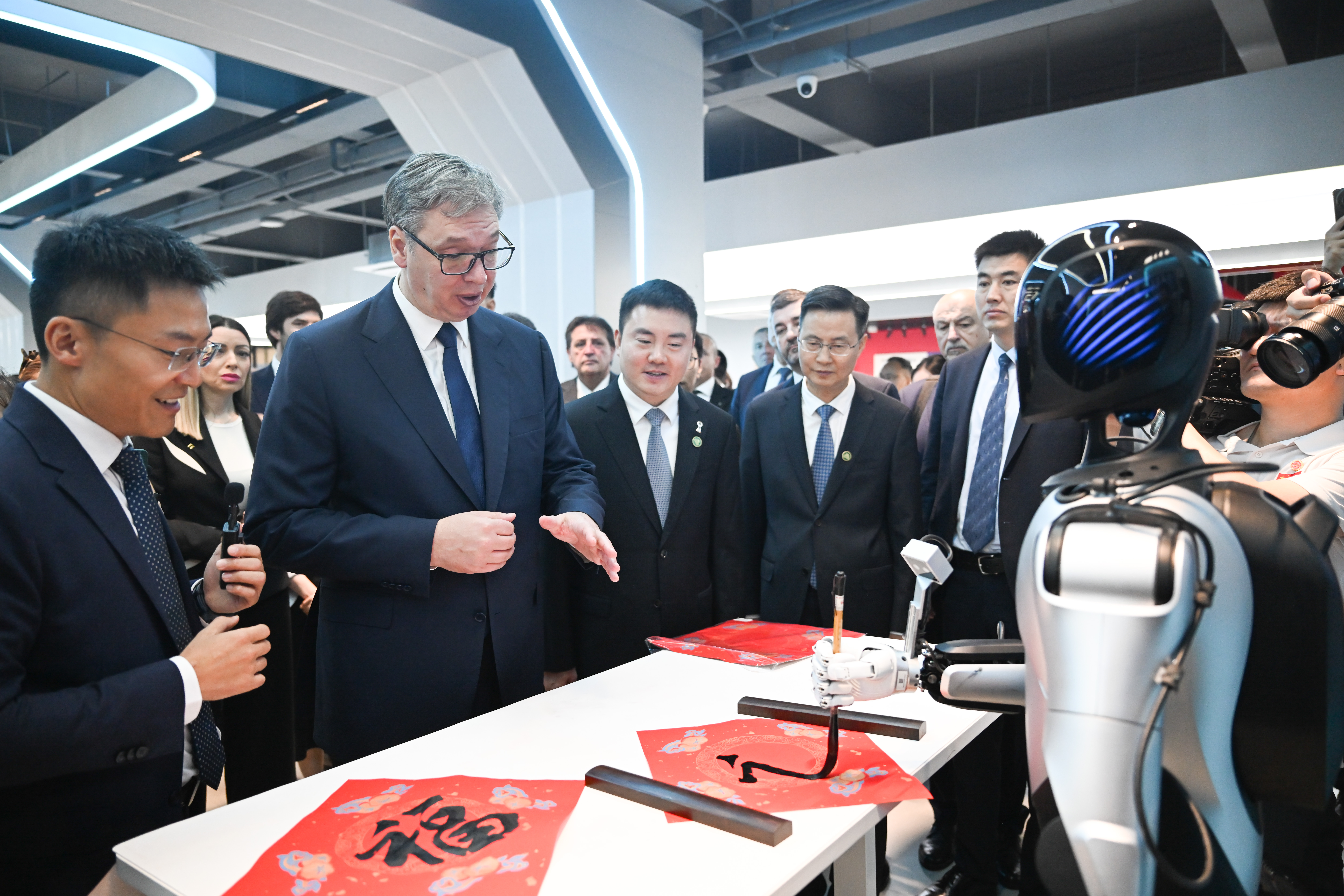 Serbian President Aleksandar Vucic watches a robot writing the Chinese character 