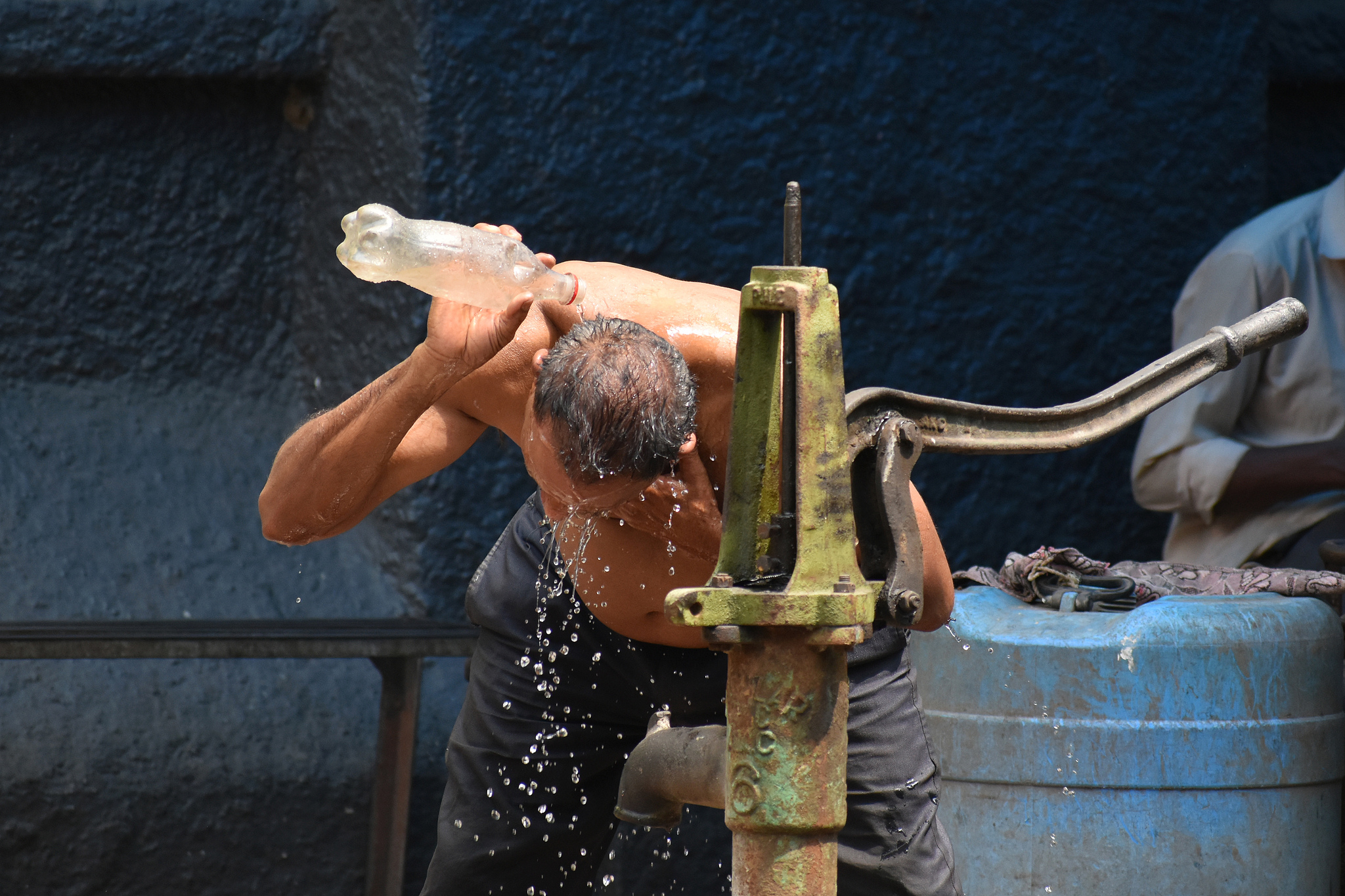 A man pours water over himself from a hand-operated water pump to cool off during a hot summer day in Kolkata, India, May 24, 2026. /VCG