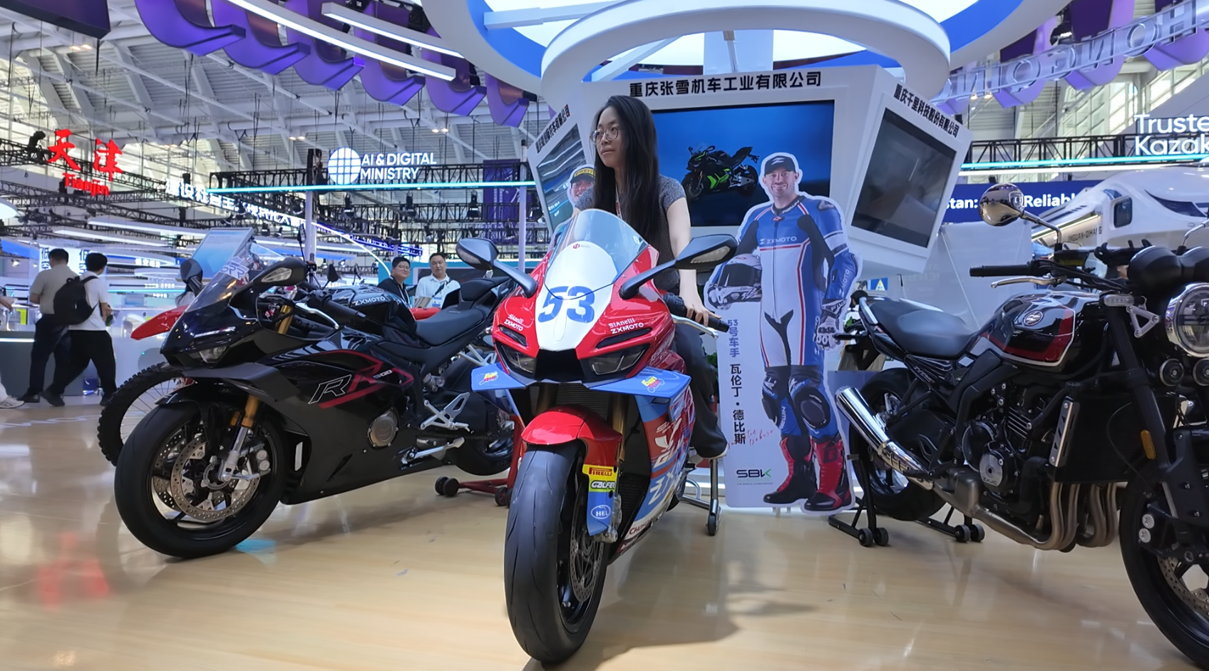 A visitor poses for photos with ZXMOTO's championship-winning model at the 2026 WIE Chongqing Pavilion, Tianjin, China, May 28, 2026. /UpGuizhou