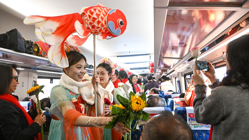 Workers greet passengers with flowers and blessings aboard a train running on the China-Laos Railway as part of celebrations ahead of the Spring Festival, February 4, 2026. /VCG