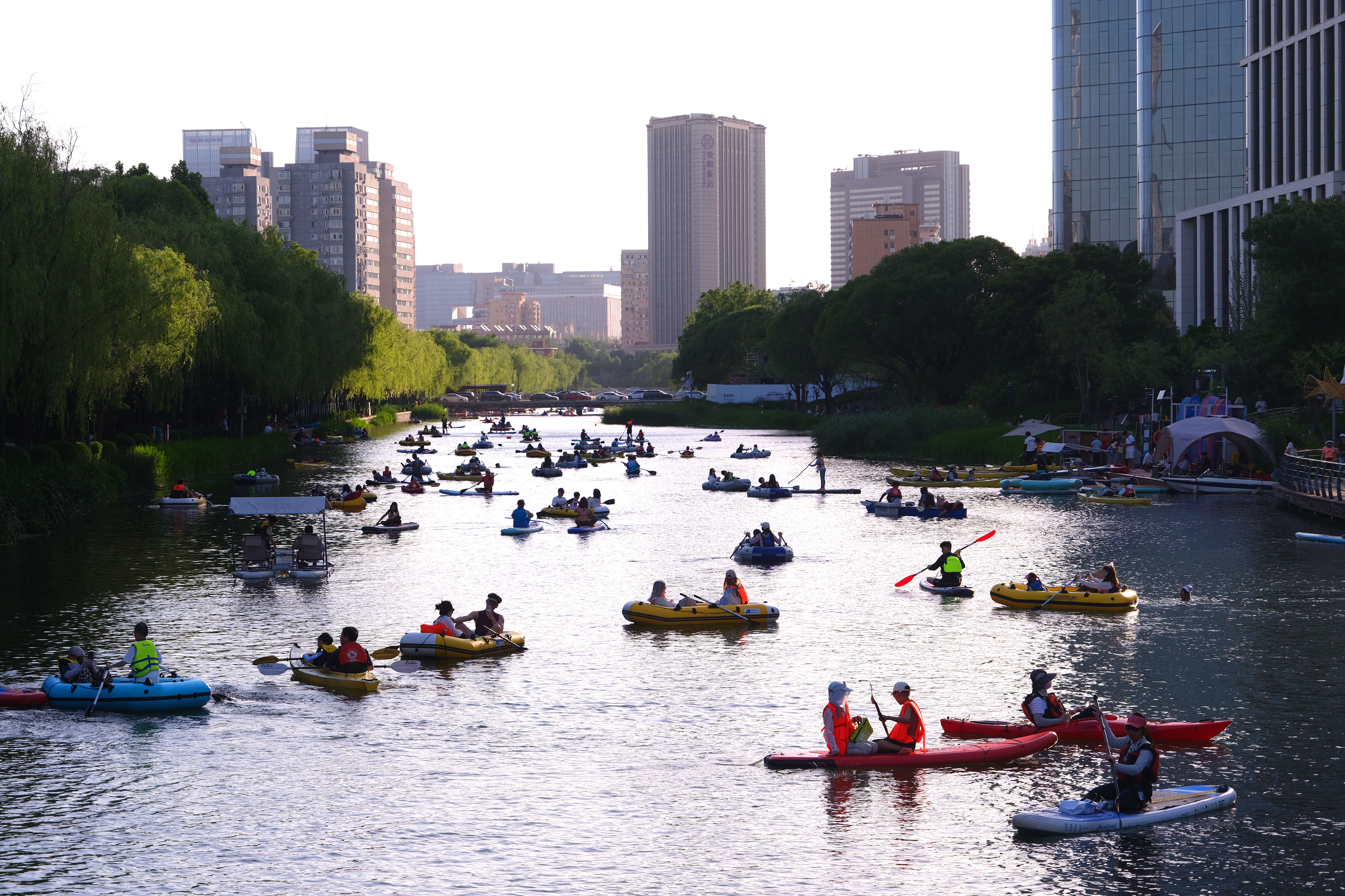 People paddle, kayak and relax along the Liangma River International Waterfront, a popular summer leisure destination in Beijing, on June 1, 2026. /IC