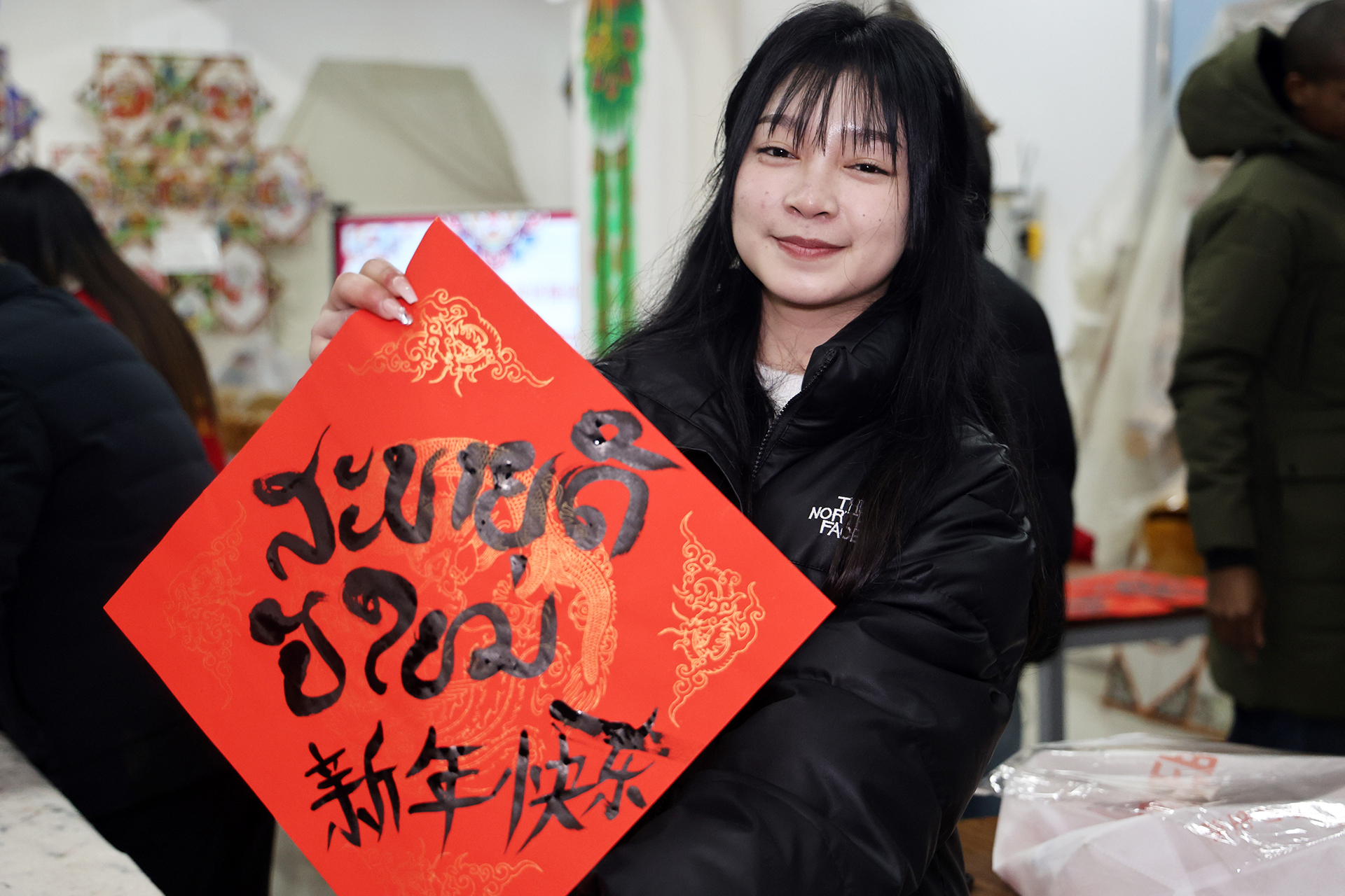 A Lao student displays a piece of red paper bearing the phrase 