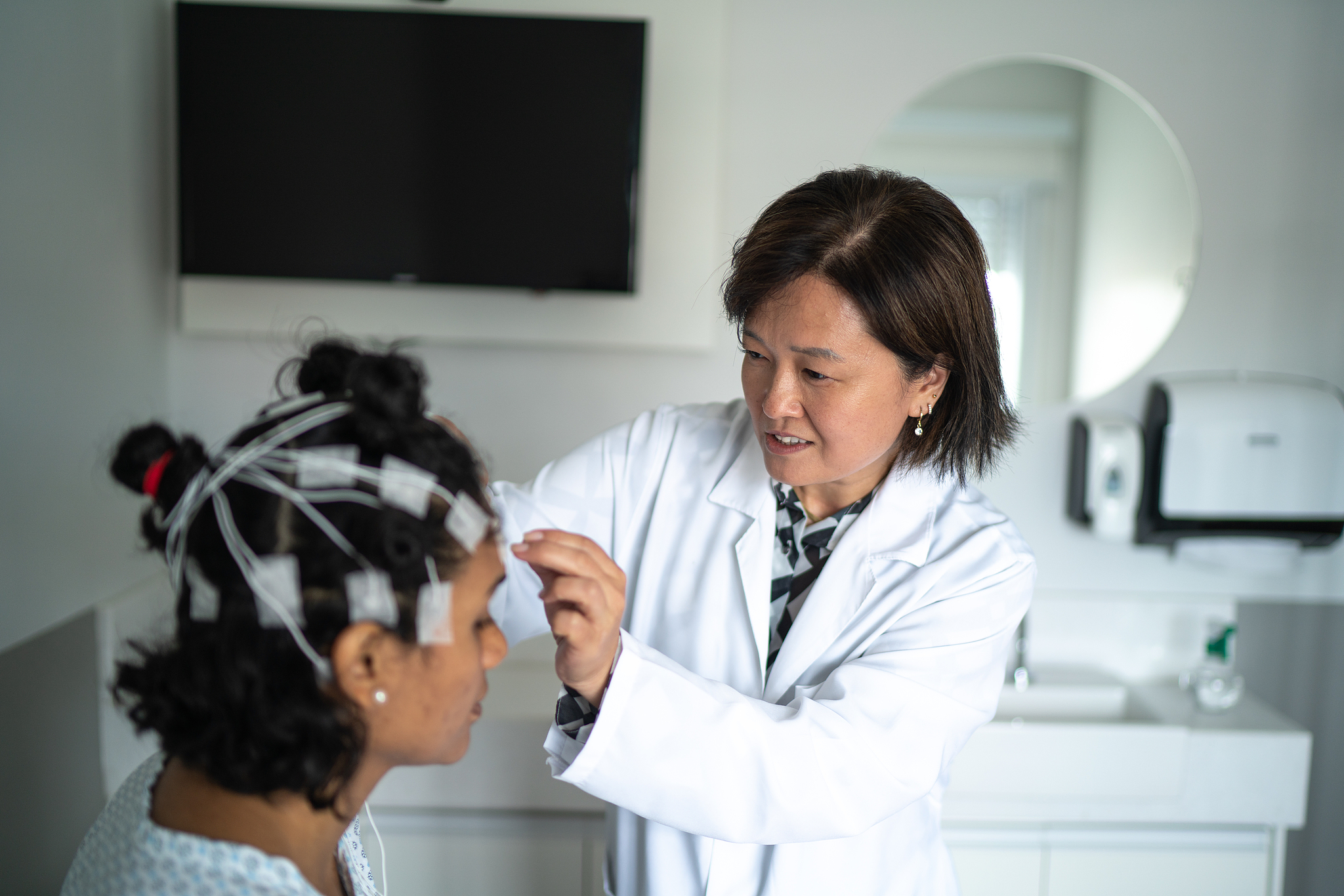 A doctor places electrodes on a patient's head for polysomnography. /VCG
