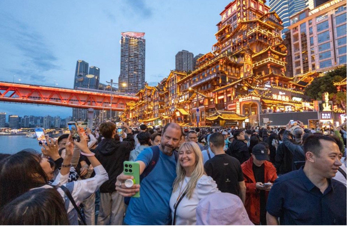 Overseas tourists take selfies in front of the Hongyadong Scenic Area in Yuzhong District of Chongqing, southwest China, April 22, 2026. /Xinhua