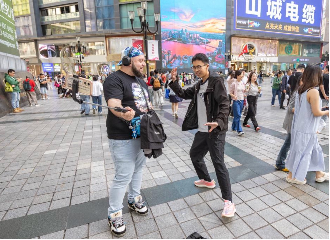A tourist from the Netherlands communicates with a Chinese blogger at Jiefangbei, a business area, in Yuzhong District of Chongqing, southwest China, April 22, 2026. /Xinhua