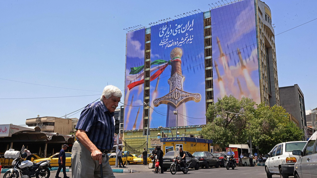 A man walks past a giant banner in Tehran, Iran on June 10, 2026. /VCG