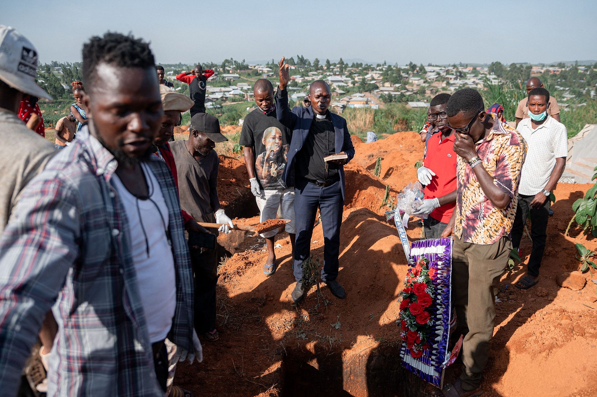 A pastor leads a funeral service for an Ebola victim as relatives gather around the body that has been placed in the grave by Red Cross volunteers involved in safe and dignified burial operations in Ituri Province, Democratic Republic of the Congo, June 13, 2026. /VCG