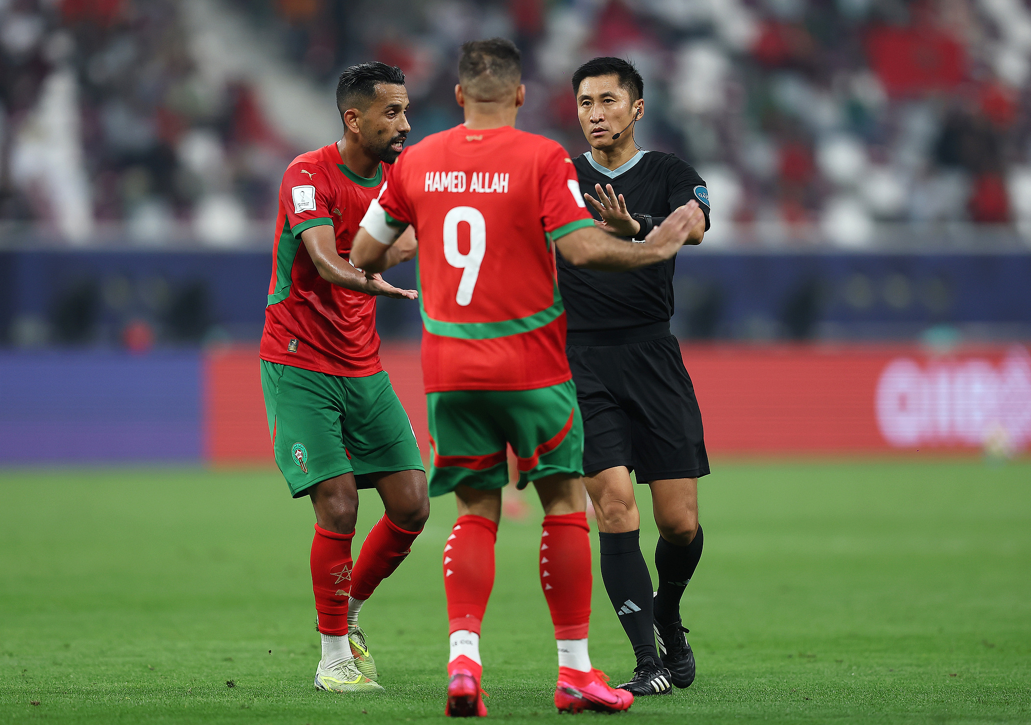 Referee Ma Ning speaks to captain Abderrazzak Hamed Allah (#9) during Morocco's match against Comoros in Group B of the 2025 FIFA Arab Cup at Khalifa International Stadium in Doha, Qatar, December 2, 2025. /VCG