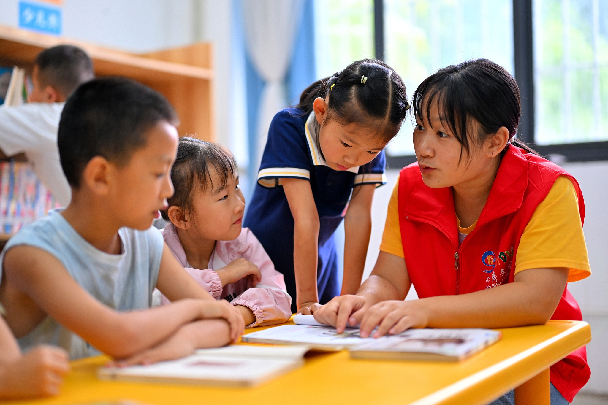 Volunteers read books with children after school at a local community center in Meishan City, southwest China's Sichuan Province. /VCG