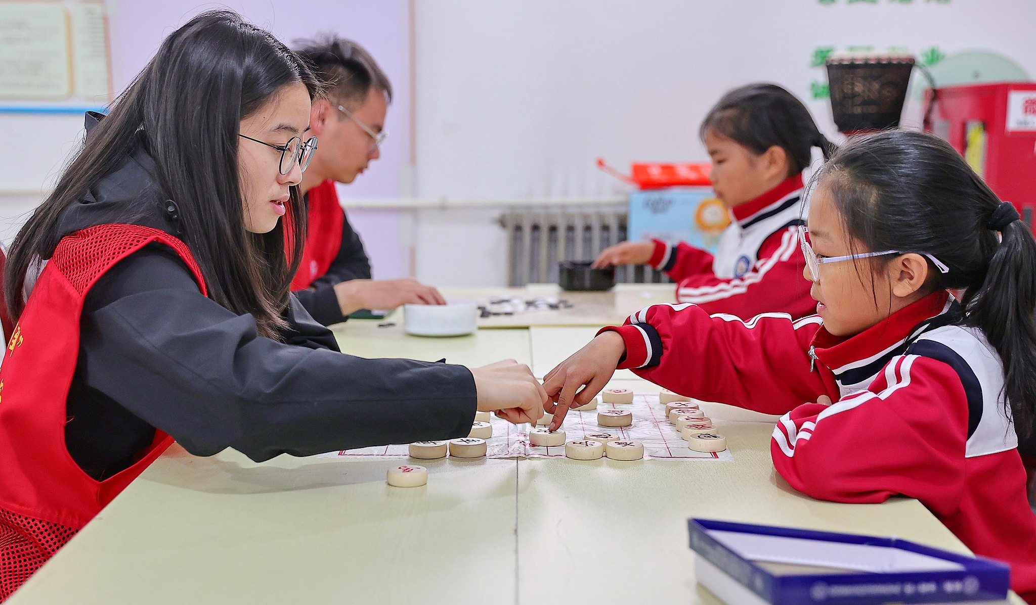 College student volunteers play Chinese chess with children at 