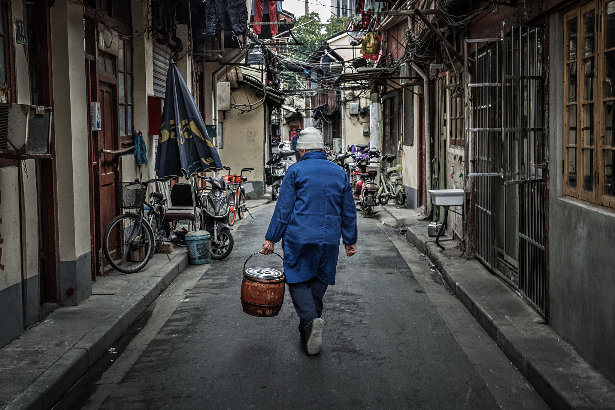 A man carries a chamber pot in older Shanghai neighborhoods in 2018. /VCG