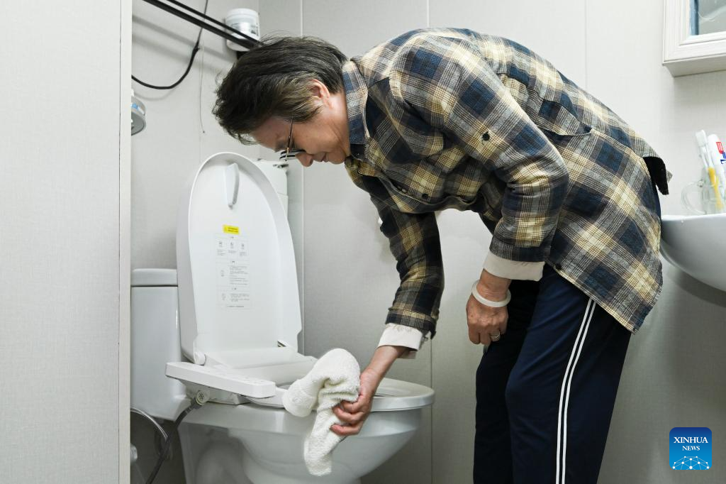 A resident wipes a flush toilet after the toilet renovation project in Yangpu District, east China's Shanghai, October 29, 2025. /Xinhua

