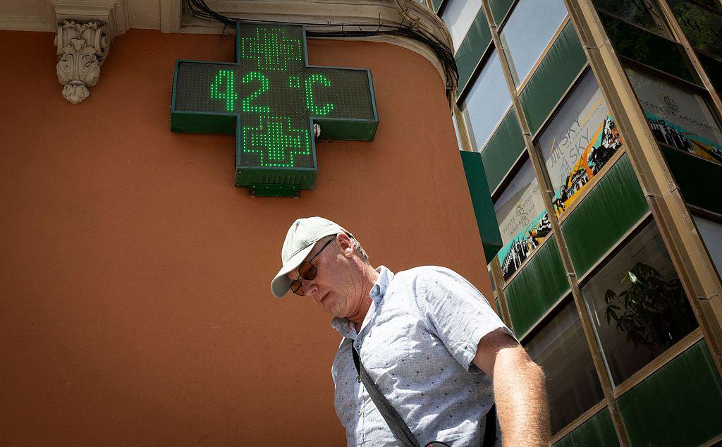 A tourist walks past a sign displaying 42 degrees Celsius in Palma de Mallorca, Spain, June 20, 2026. /VCG