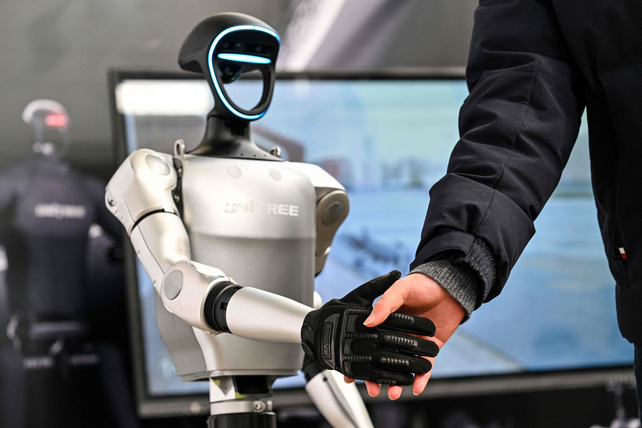 A man shakes hands with a humanoid robot from Unitree Robotics during the Global Developer Conference, organized by the Shanghai AI Industry Association, in Shanghai, China, February 21, 2025. /VCG