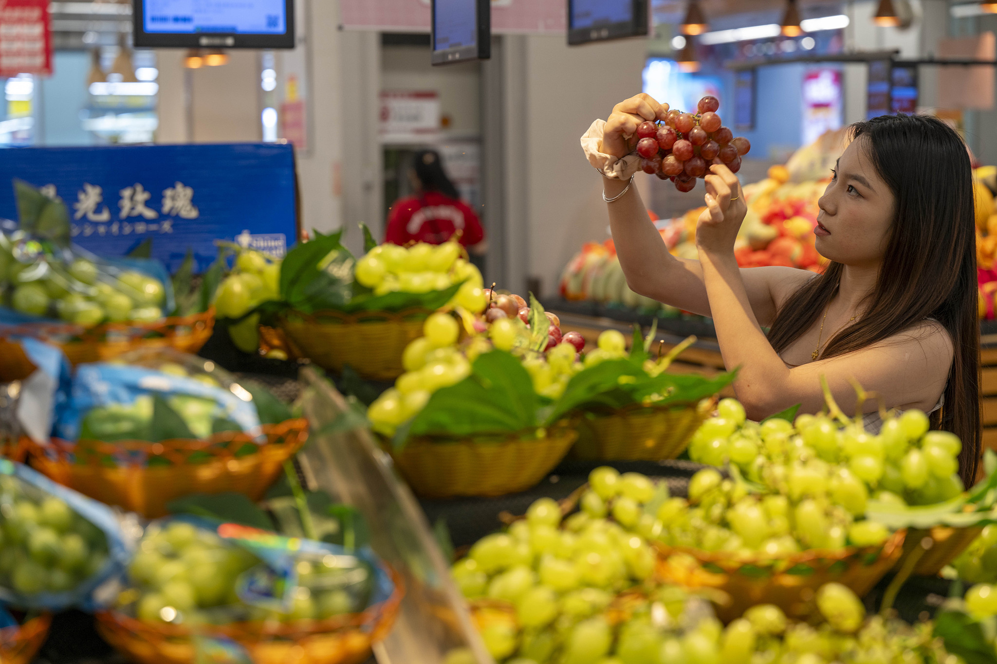 Shoppers select fresh fruits at a supermarket in China. /VCG
