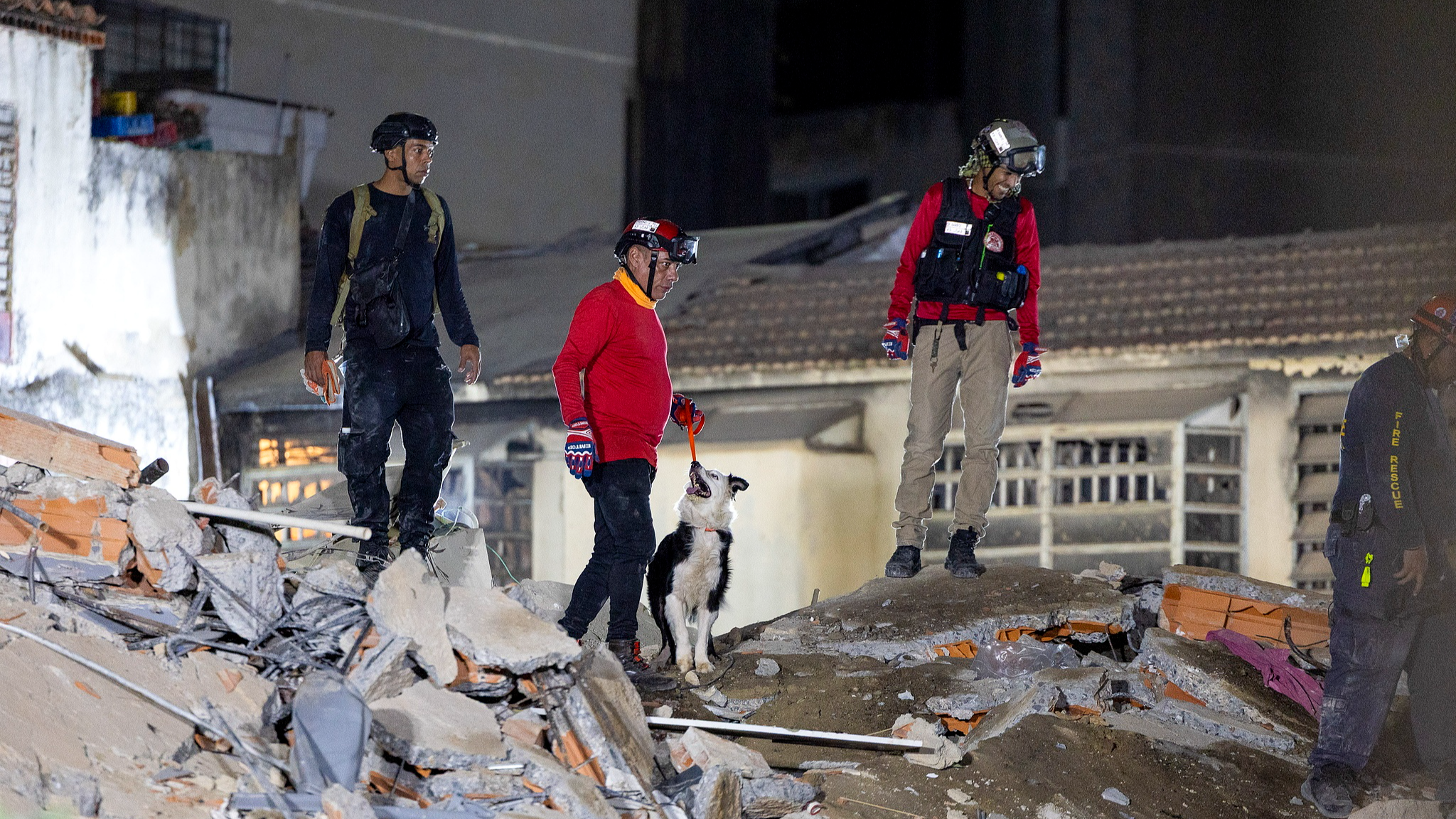 Emergency service members with a dog search through the rubble of a building following the twin 7.2- and 7.5-magnitude earthquakes that struck the country, in Caracas, Venezuela, June 25, 2026. /VCG