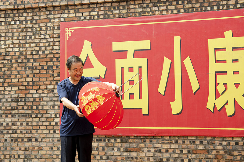 A worker was showing the red lanterns he had completed outside a poverty alleviation lantern workshop in Wanrong County, Shanxi Province, June 29, 2019. /CFP