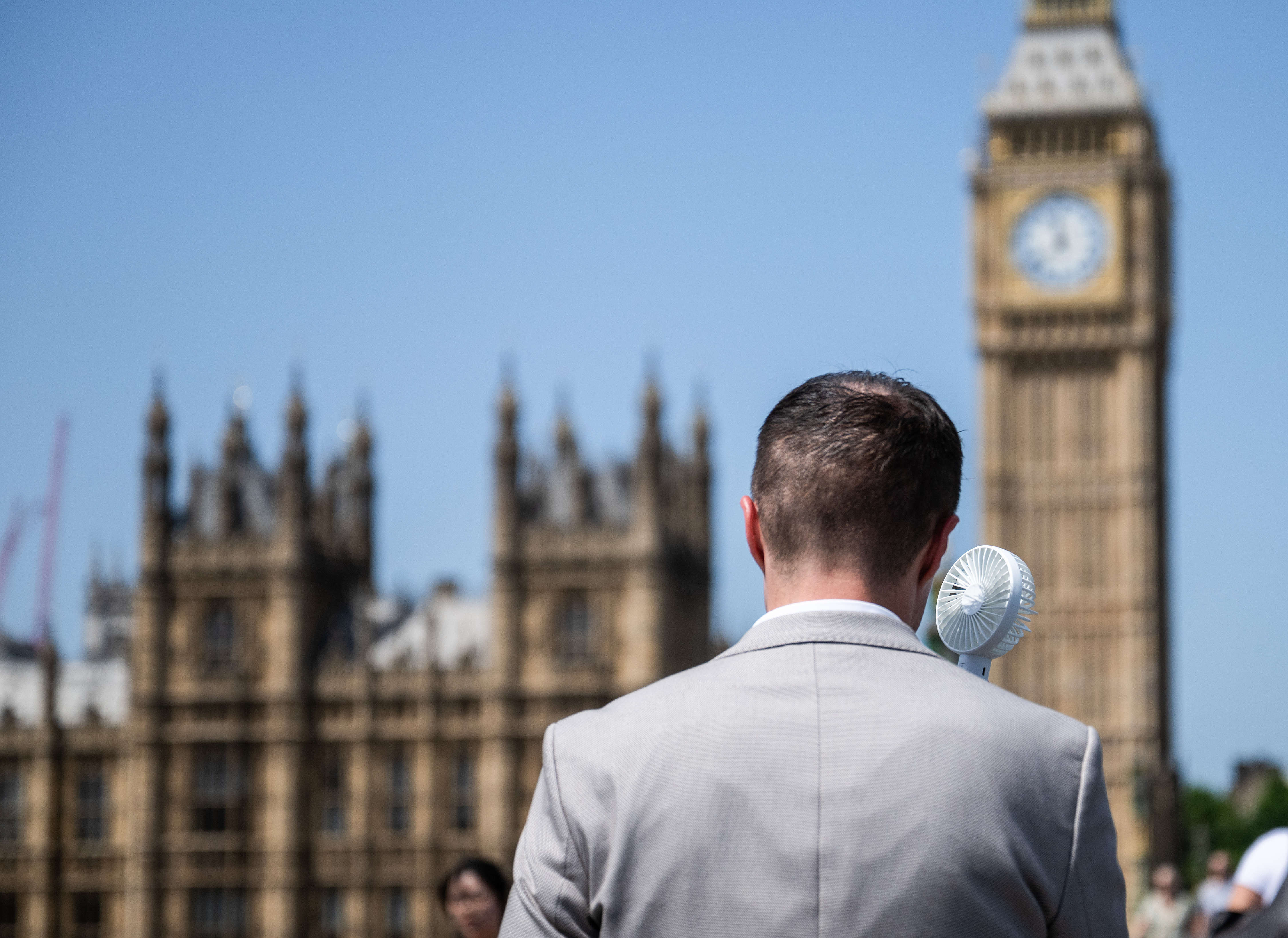 A man uses a portable electric fan on Westminster Bridge in London, the UK, June 23, 2026. /VCG