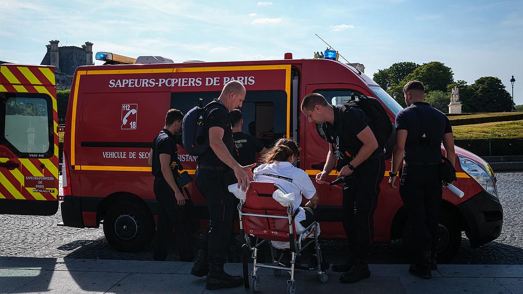 Firefighters from the Paris Fire Brigade assist a person, who became unwell during an intense heatwave, into an ambulance, Paris, France, June 25, 2026. /VCG