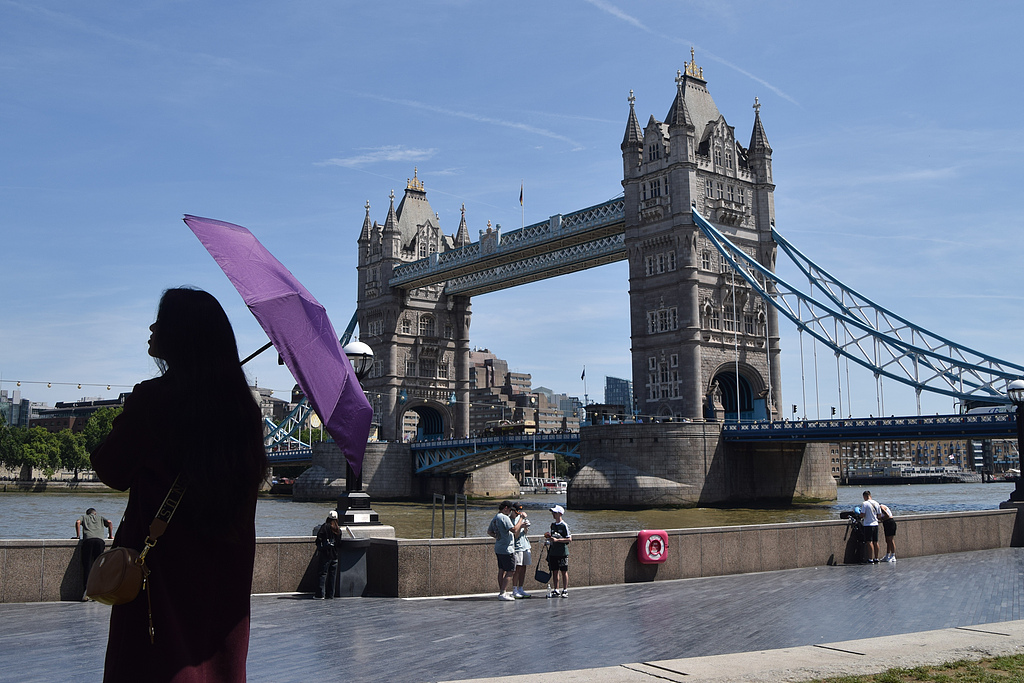 A woman shelters from the sun under an umbrella near Tower Bridge in London as the heatwave continues across Europe, June 27, 2026. /VCG