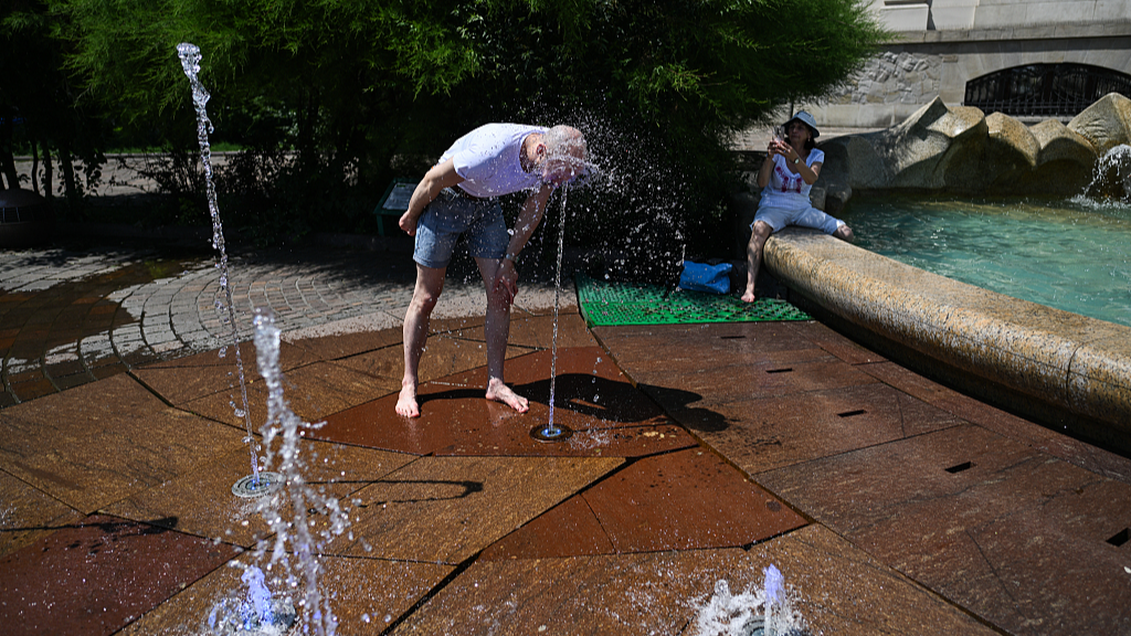 A man refreshes himself in a water fountain as high temperatures continue in Krakow, Poland, June 28, 2026. /VCG