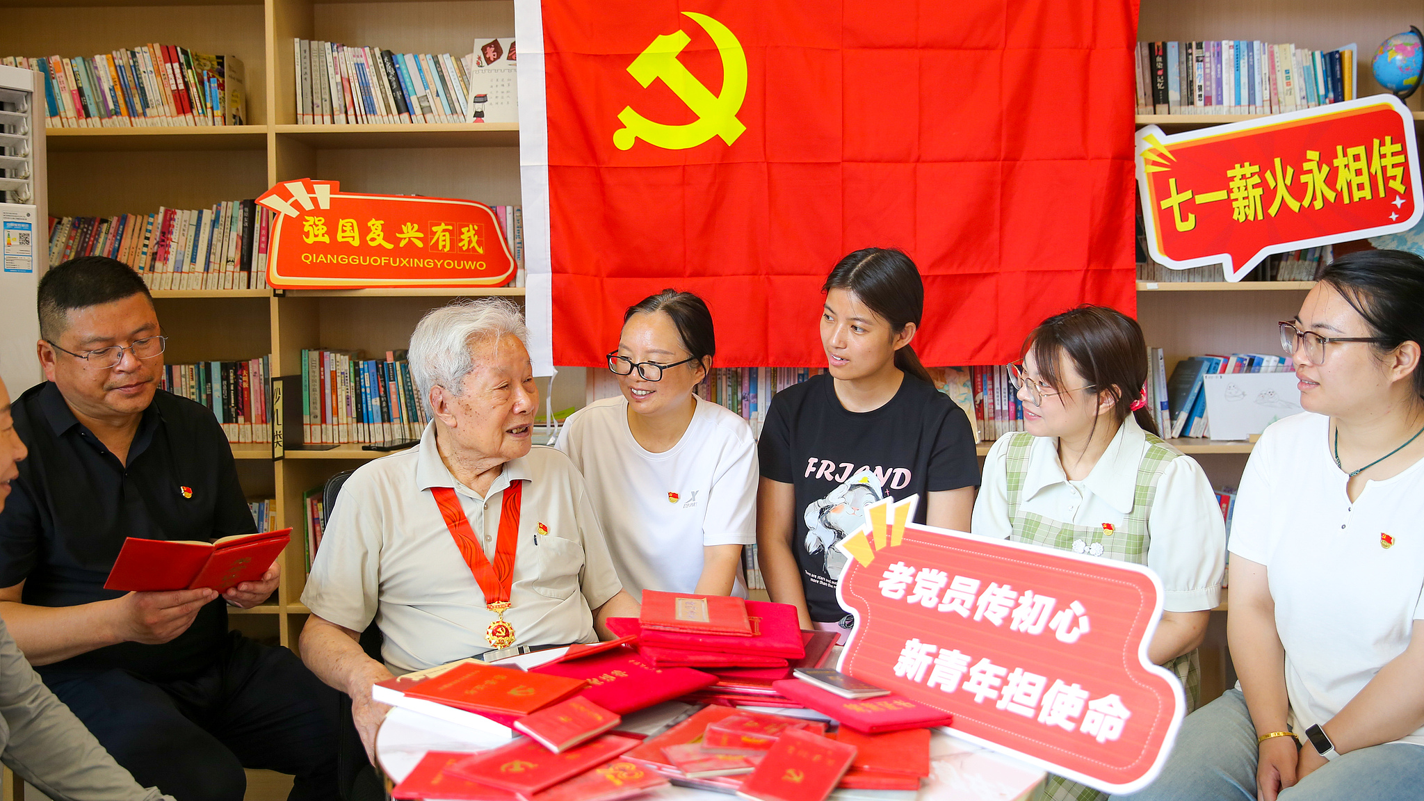 A 95-year-old Communist Party member, Lu Zhishen, displays his treasured certificates of honor and commemorative medals while sharing stories of his past with young Party members at a reading room in Rugao, Jiangsu Province, China, June 29, 2026. /VCG
