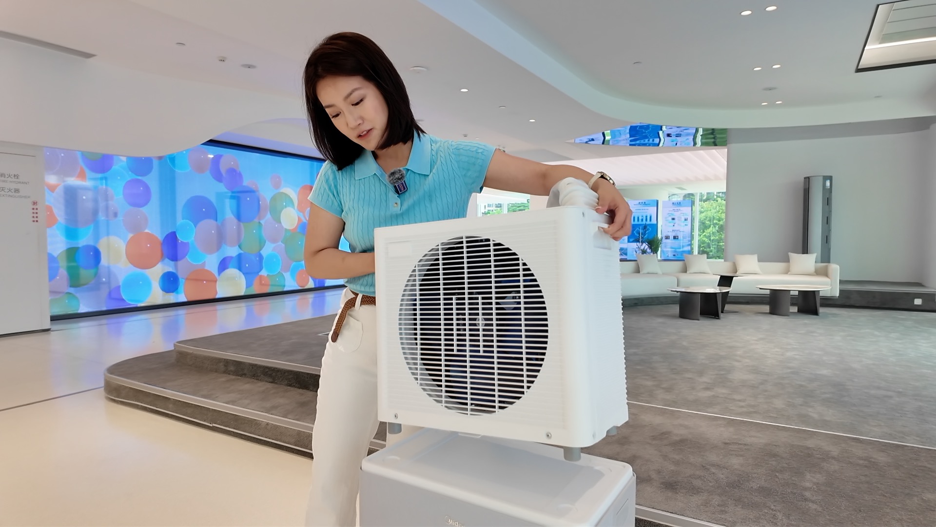 A CGTN reporter lifts the outdoor condenser of a mobile split air conditioner, June 29, 2026. /CGTN