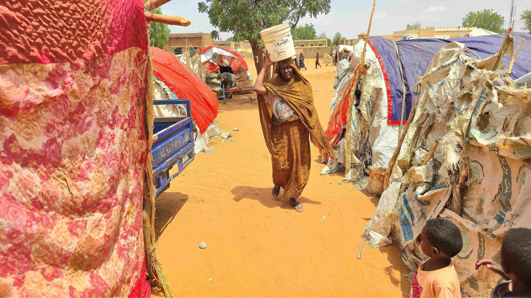 A Sudanese woman walks as she carries a plastic canister in al-Rahmaniyah camp for displaced people, near the city of El-Obeid in the southern Kordofan region, on June 25, 2026. /VCG