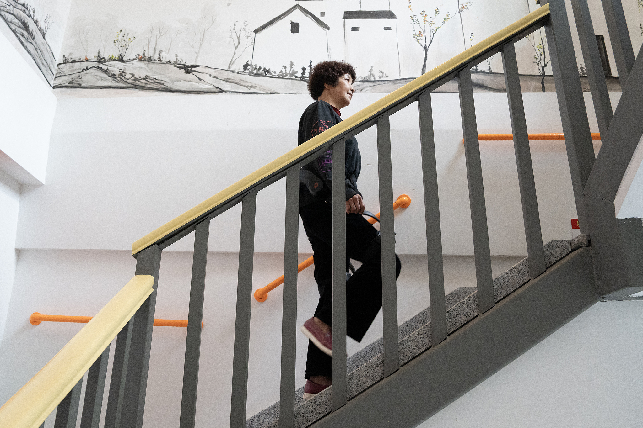 A woman experiences a mobility-assisted exoskeleton device while climbing stairs at the elderly care service center in Xihu District, Hangzhou, east China's Zhejiang Province, March 12, 2025. /VCG