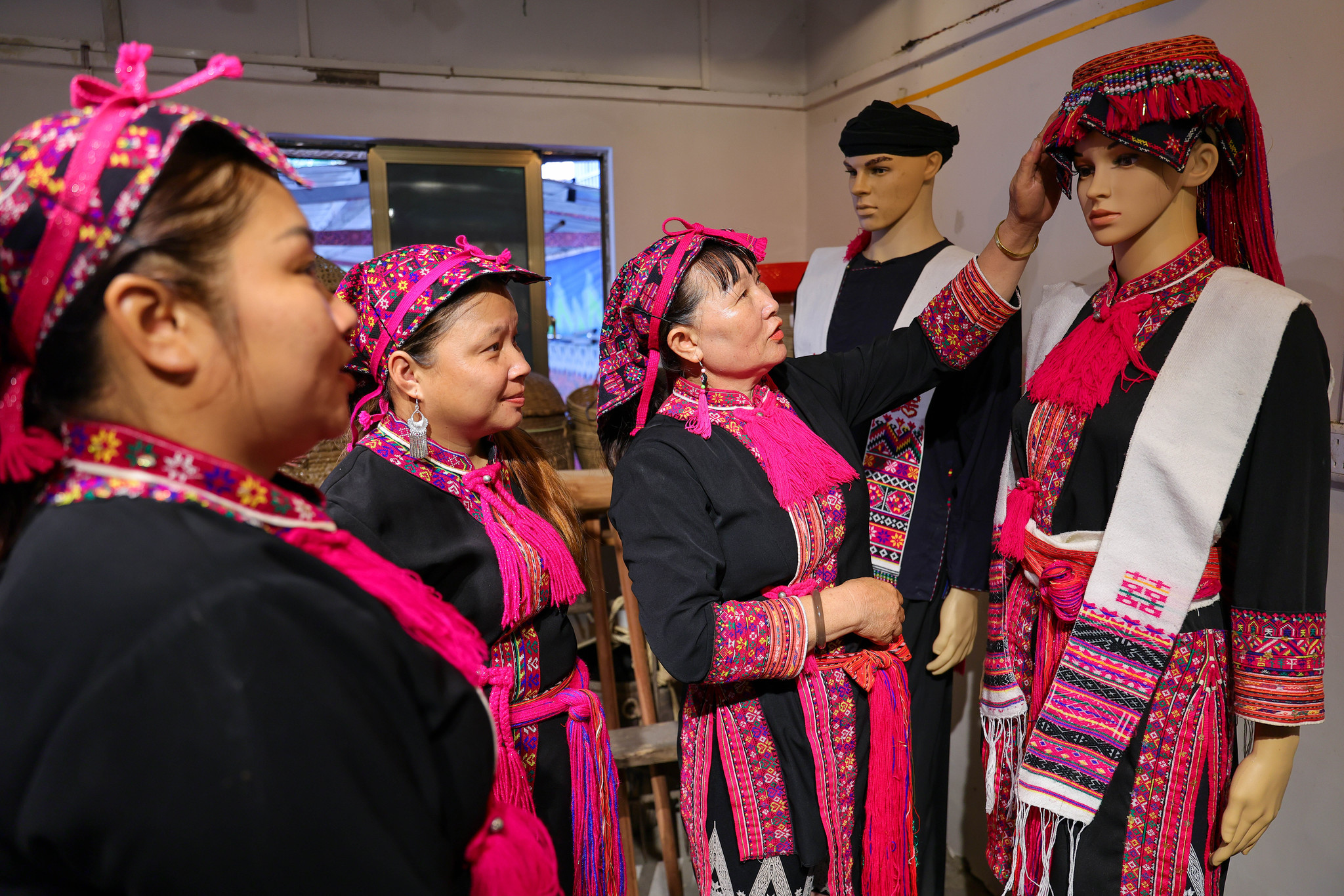 Inheritor Zhao Haijin introduces Miao embroidery pieces to learners at her workshop in Hainan Province on July 1, 2026. /VCG