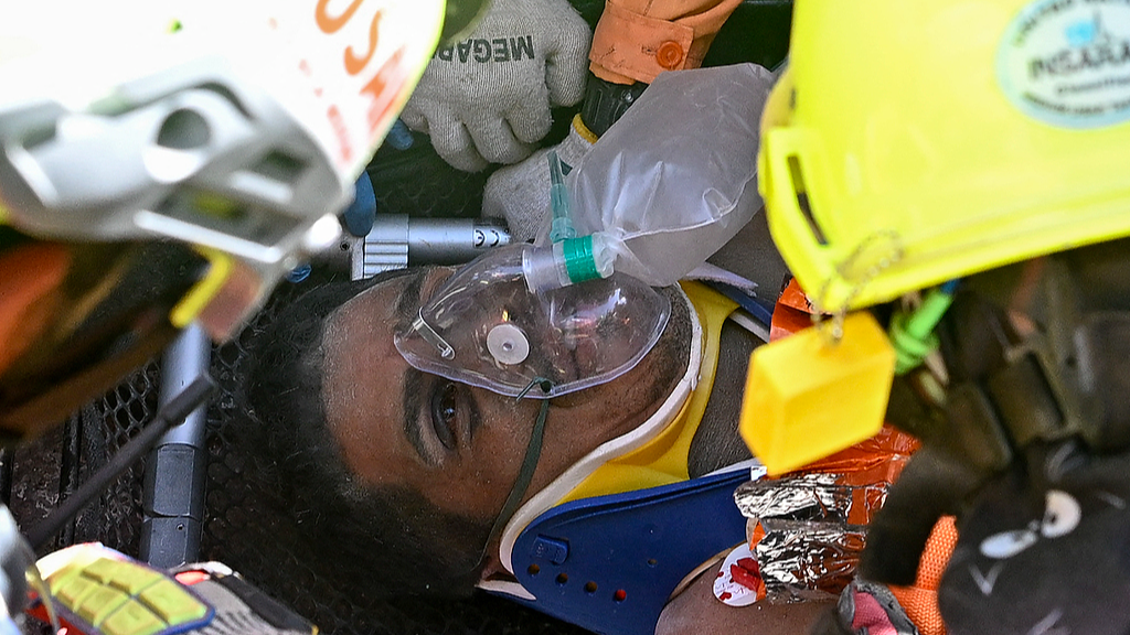 Hernan Gil, a survivor of Venezuela's twin earthquakes, is assisted by members of international rescue teams before being rushed into an ambulance in Catia La Mar, La Guaira State, Venezuela, July 2, 2026. /VCG