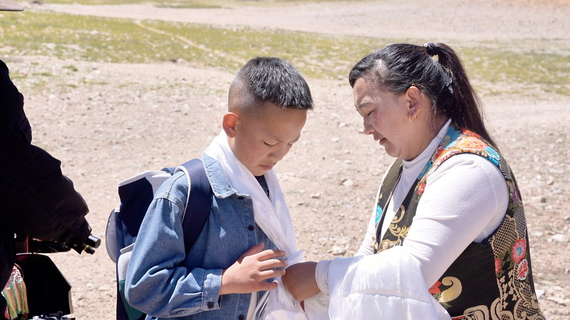 Tenzin Lobsang's mother places a white khata, a traditional Tibetan ceremonial scarf symbolizing good wishes, around his neck as his family bids him farewell before he leaves for school, Baingoin County, Nagqu, Xizang Autonomous Region, August 15, 2025. /CGTN
