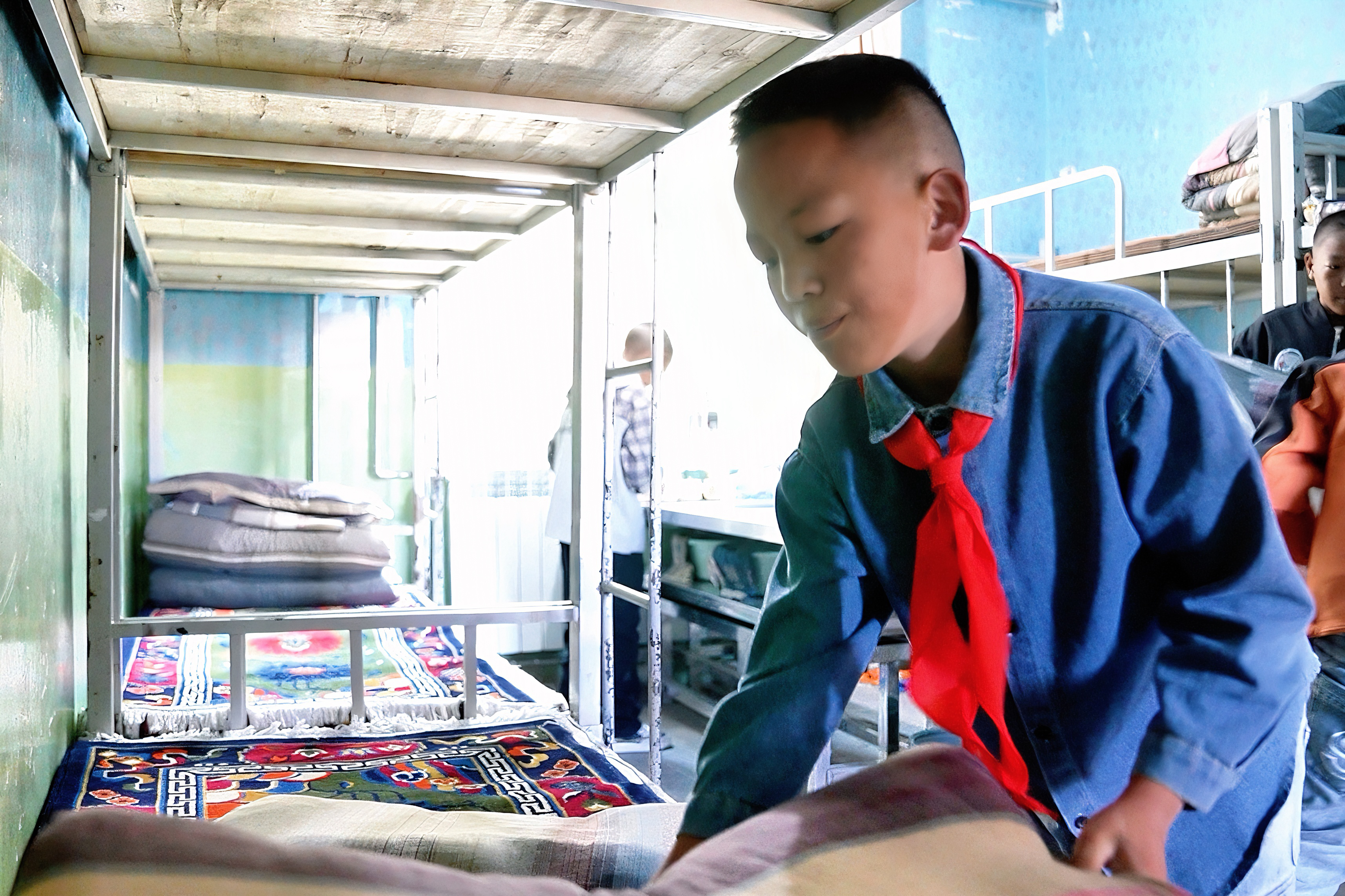 Tenzin Lobsang makes his bed in the student dormitory, where he lives with classmates during the school term, Baingoin Sinopec Primary School, Baingoin County, Nagqu, Xizang Autonomous Region, August 16, 2025. /CGTN