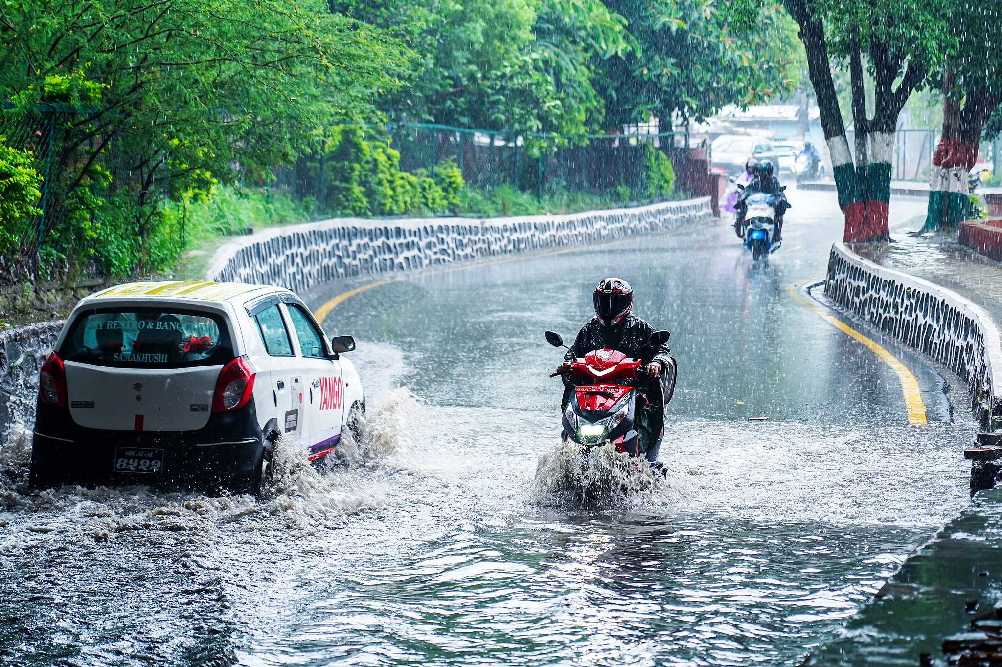 People wearing raincoats and vehicles move through rain-soaked streets amid heavy rainfall in Kathmandu, Nepal, on June 29, 2026. /VCG