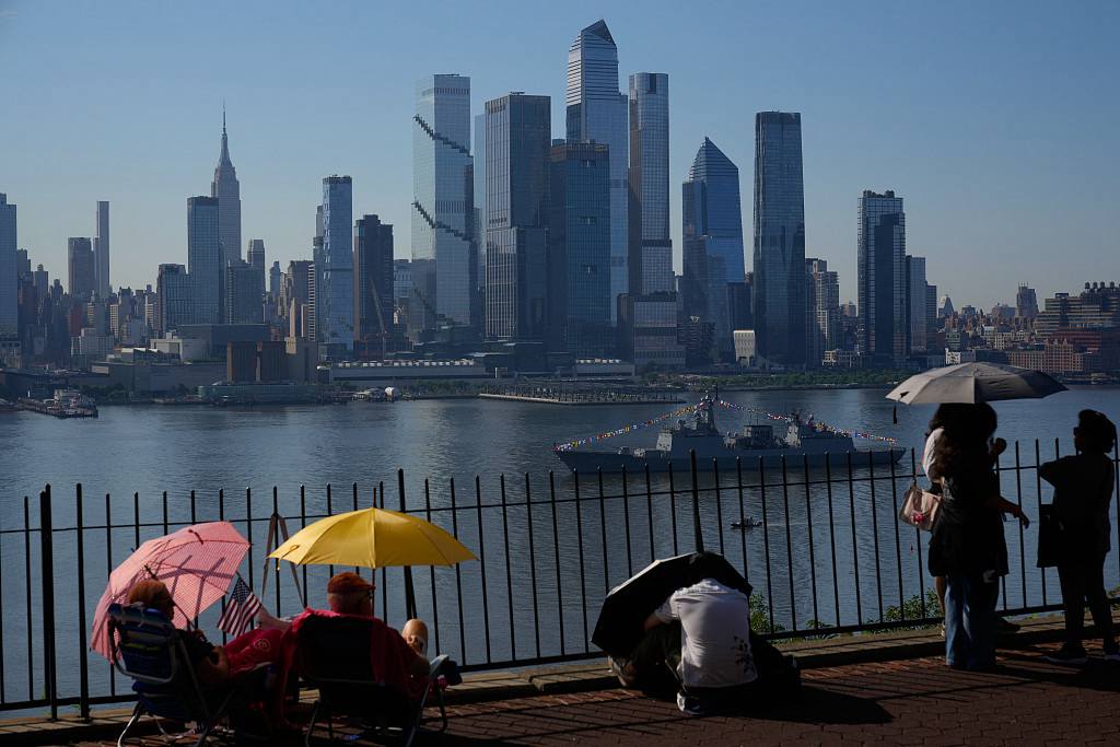 People take cover from the heat under umbrellas as they wait for a parade of tall ships and flyovers in Weehawken, New Jersey, July 4, 2026. /VCG