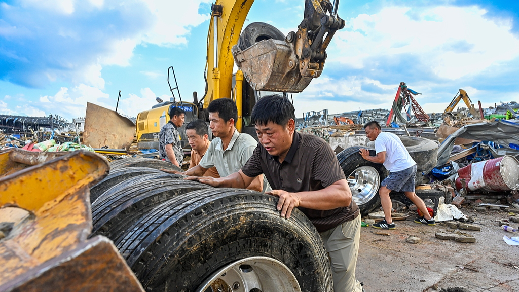 People moving tires away from site after multiple heavy-duty trucks were overturned by a tornado in Huanggang City, Hubei Province, China, July 7, 2026. /VCG