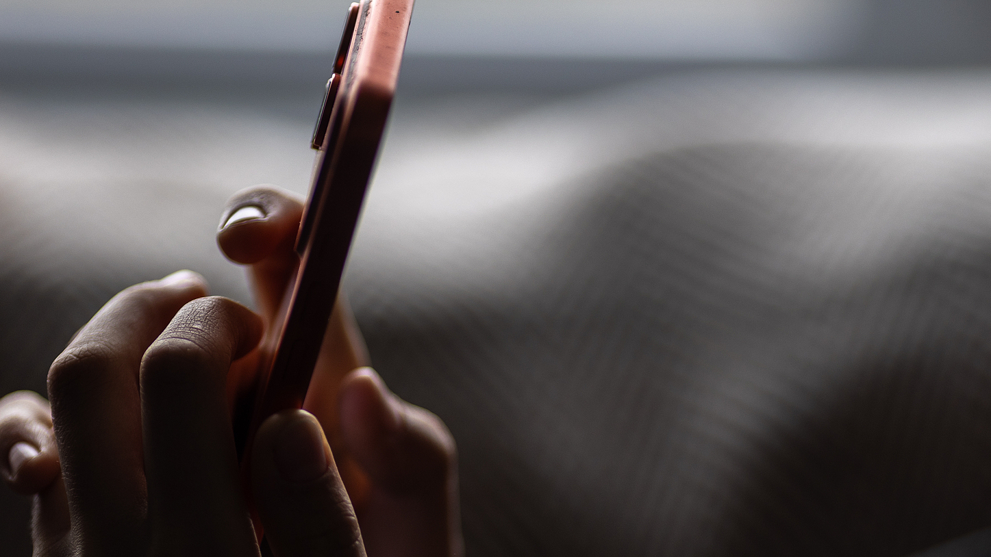 A person uses a smartphone in a low-light setting. /VCG