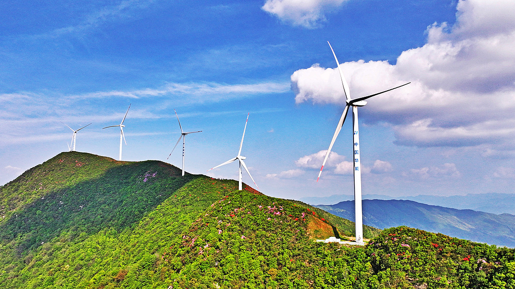Wind turbines stand atop green hills amid blue skies at the Gaolong Mountain Wind Farm in Yongfeng County, Ji'an City, Jiangxi Province, China, April 24, 2026. /VCG