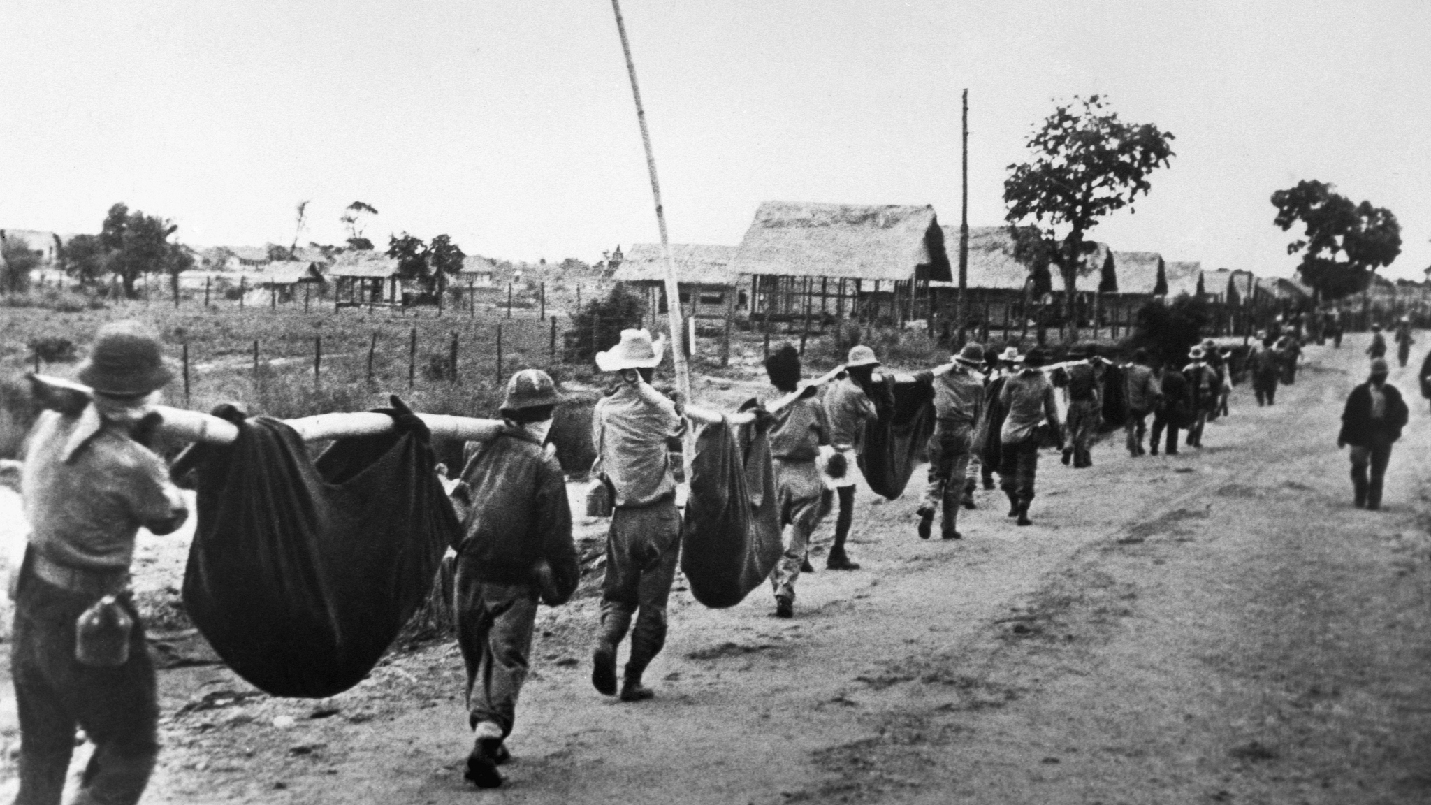 American prisoners use improvised litters to carry their comrades who, from the lack of food or water on the march from Bataan, fell along the road, in the Philippines, May 1942. /VCG