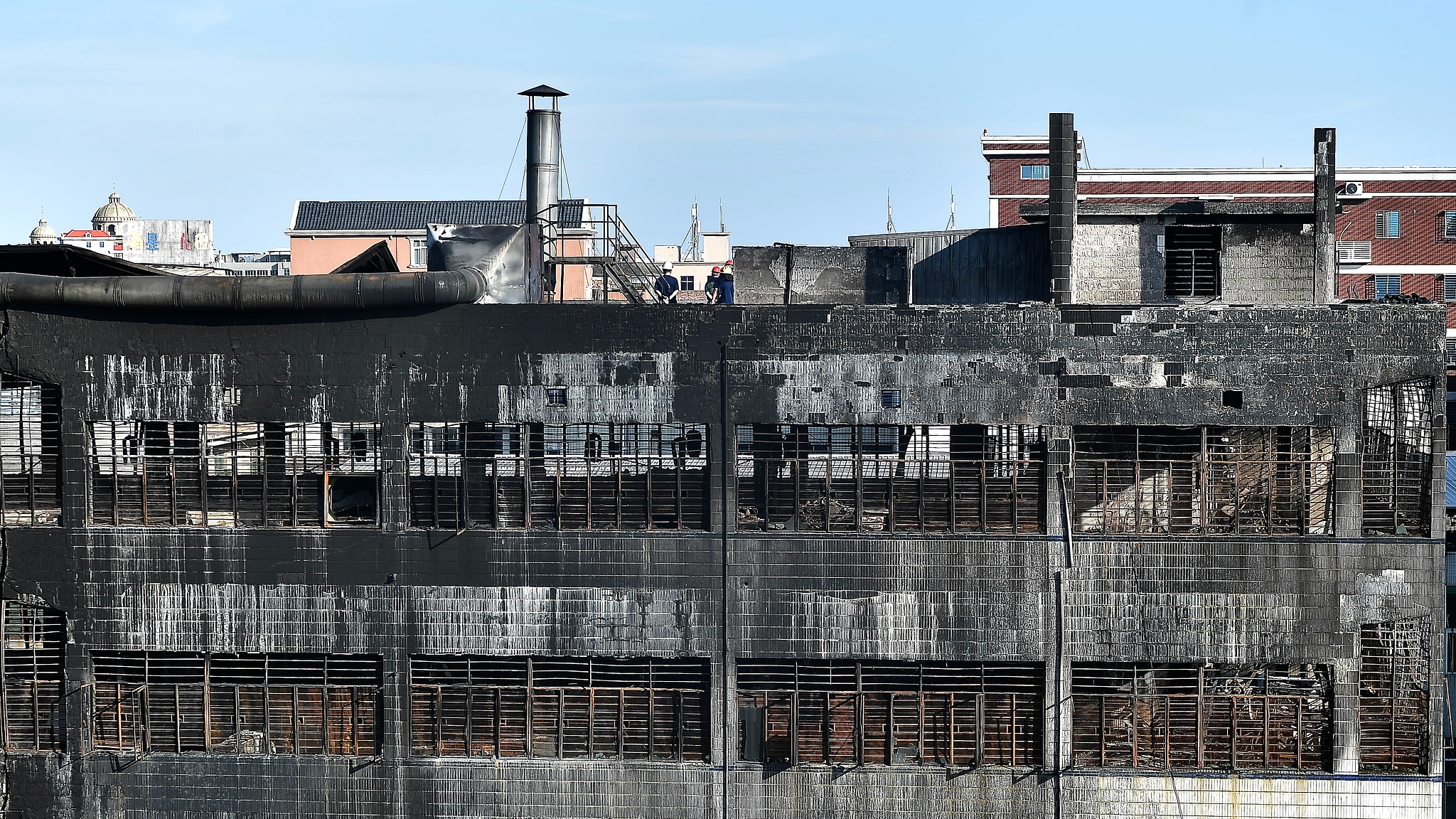 Staff members examine the scene on the rooftop of a shoe factory damaged by a major fire in Jinjiang, east China's Fujian Province, July 10, 2026. /VCG