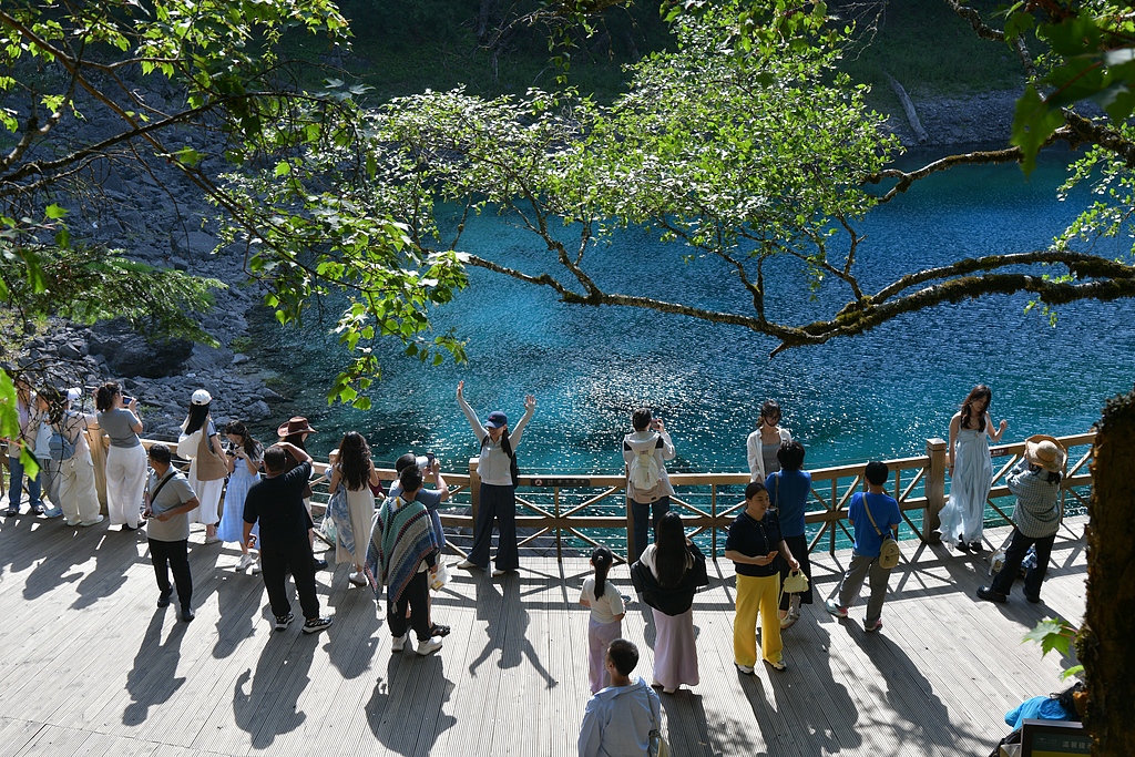 Visitors take photos and admire the scenery at Jiuzhaigou National Park in southwest China's Sichuan Province, a destination known for its cool climate, July 9, 2026. /VCG

