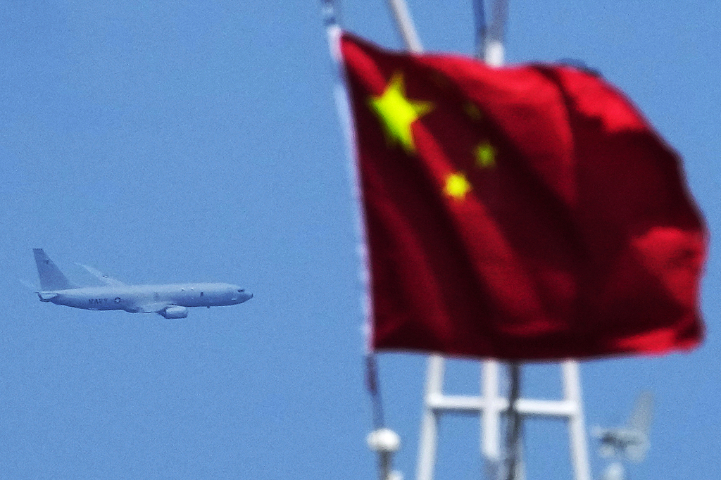 A US Navy plane passes by a Chinese flag as it flies over the area of China's Ren'ai Jiao in the South China Sea, August 22, 2023. /VCG
