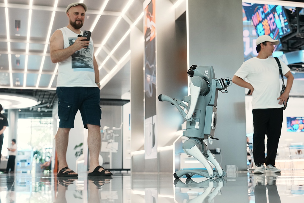 A robot dog is seen interacting with foreign visitors at the WAIC, on July 17, 2026, in Shanghai, China. /VCG