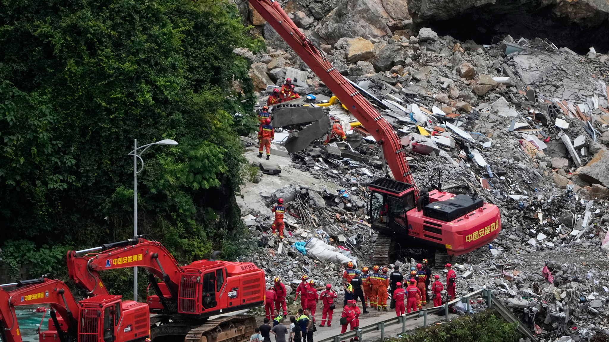 Rescuers use a heavy duty machine to clear the rubble to search for trapped victims at the scene of a landslide in Pengshui County in southwestern China's Chongqing, July 18, 2026. /VCG