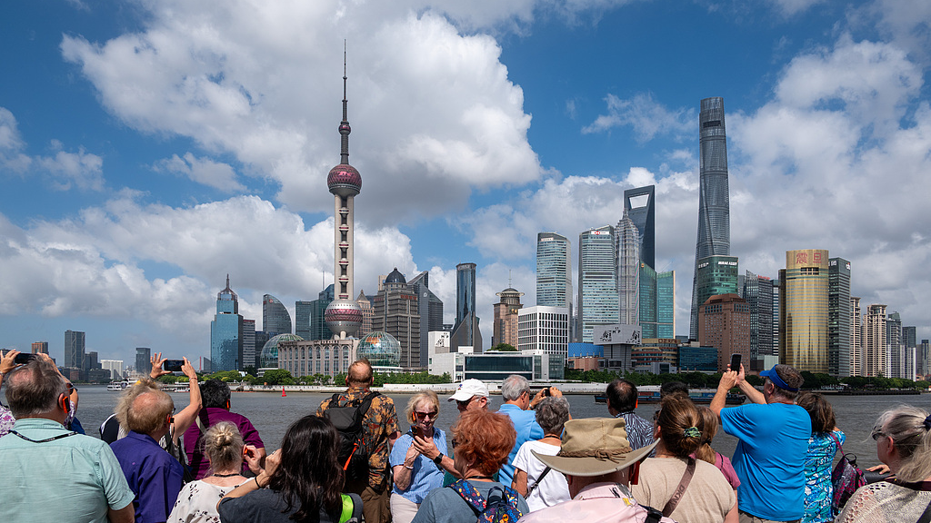 Foreign tourists take photos on the Bund waterfront platform against the backdrop of the Lujiazui skyline in Shanghai, July 10, 2026. /VCG