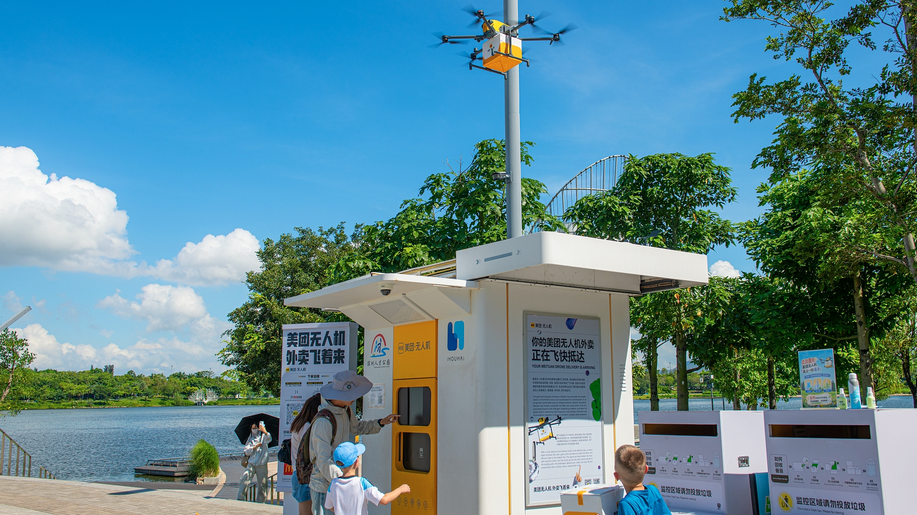 Foreign visitors use a drone food delivery service at Shenzhen Talent Park, Shenzhen, south China's Guangdong Province, June 21, 2026. /VCG
